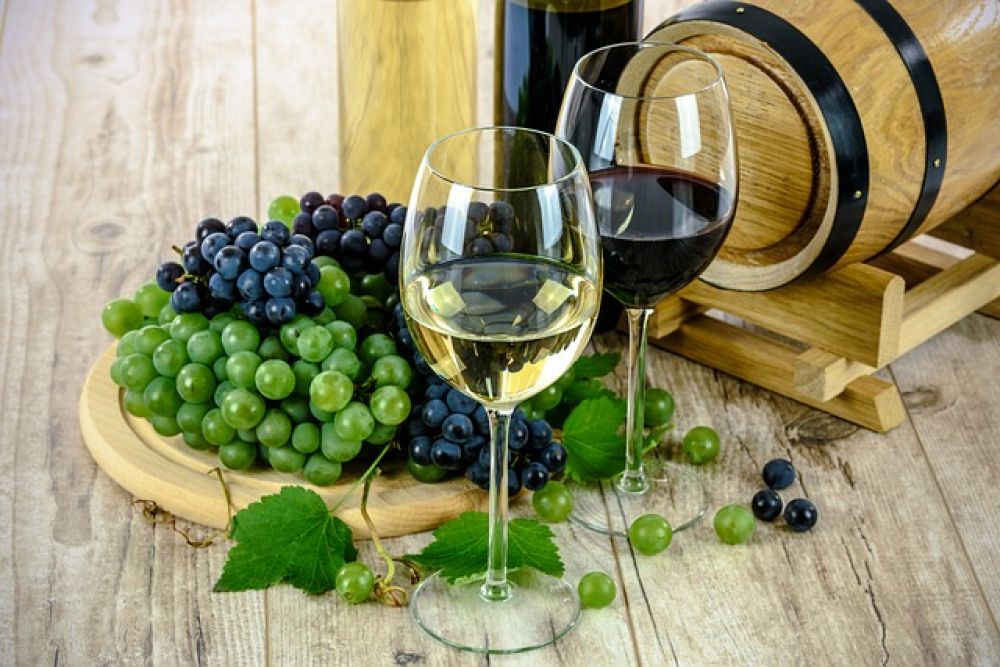 Weingläser und Weintrauben vor Holzfass