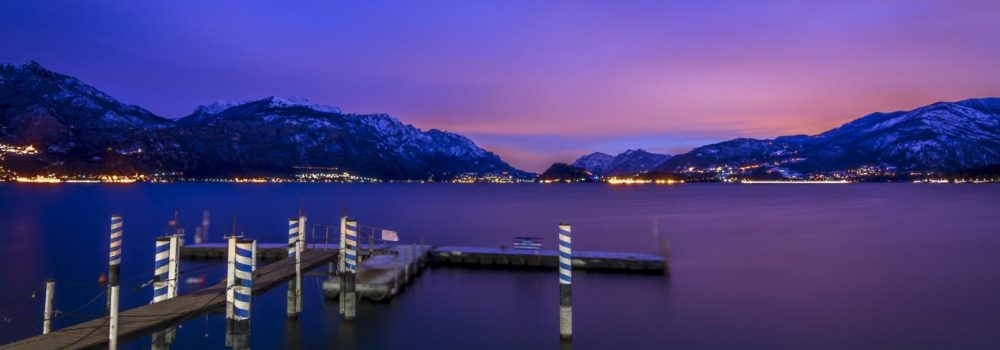 Strange colors during a sunset on Como Lake in Lombardy, Italy. The Pier of Menaggio is on the foreground. Shot is take with long exposure.